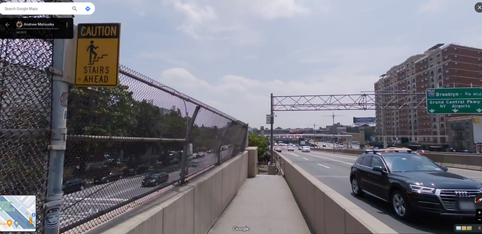 A bridge sidewalk/bike lane next to a NYC highway. It looks pretty narrow, and suddenly disappears at the end with a railing. A yellow sign warns, "CAUTION Stairs Ahead."