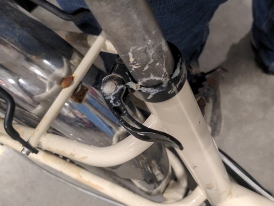 Seat tube of a white frame bicycle with silver fenders and a silver seat post.  There's a black quick-release handle that's splattered in a white gunk (bird poop). 