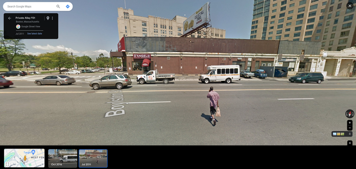 Google streetview from 2011 of Boylston St at Brookline Ave; 4-6 lanes of cars, and a low-rise decrepit warehouse next to a D'Angelos sandwich shop.