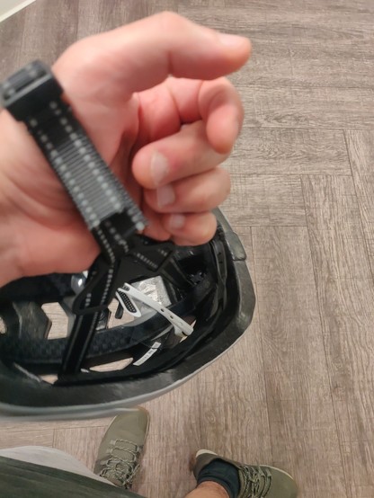 A hand with a bike helmet strap around the wrist. Inside of the helmet, a pair of sunglasses.