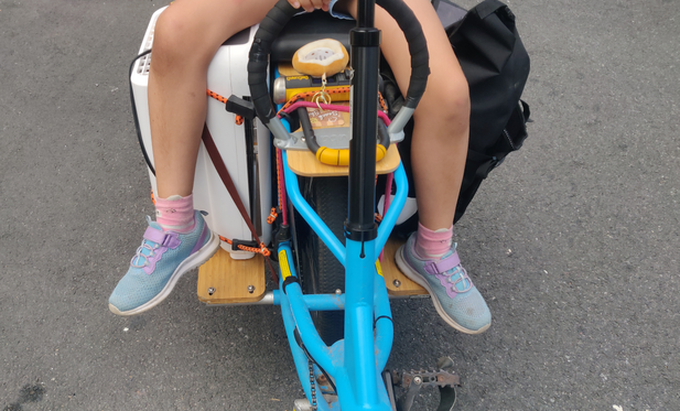 Another shot of the rear of the Kombi. This time you can see more of the blue frame, and both sides of the back. The white air filter is still on the right side of the bike, and on the left side a black Orlieb bag is attached. A child's legs are slung over both things.